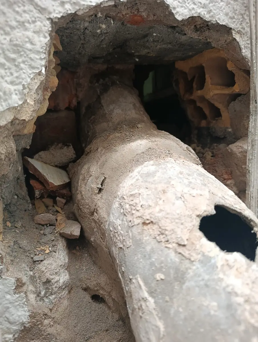 Bajante antiguo roto y agujereado dentro de la pared