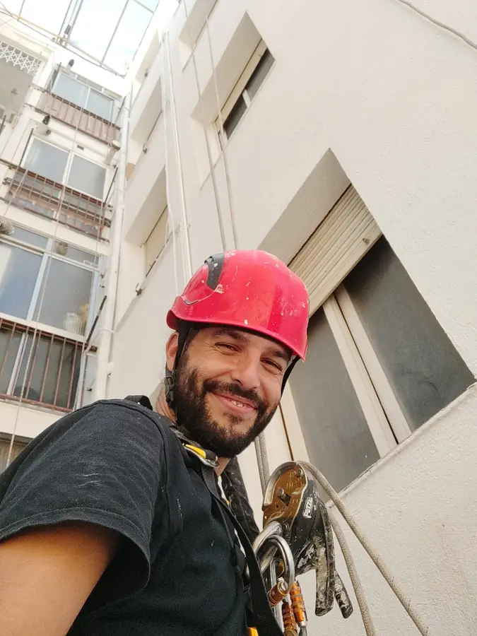 Técnico de trabajos verticales colgado en lo alto de un patio de luces