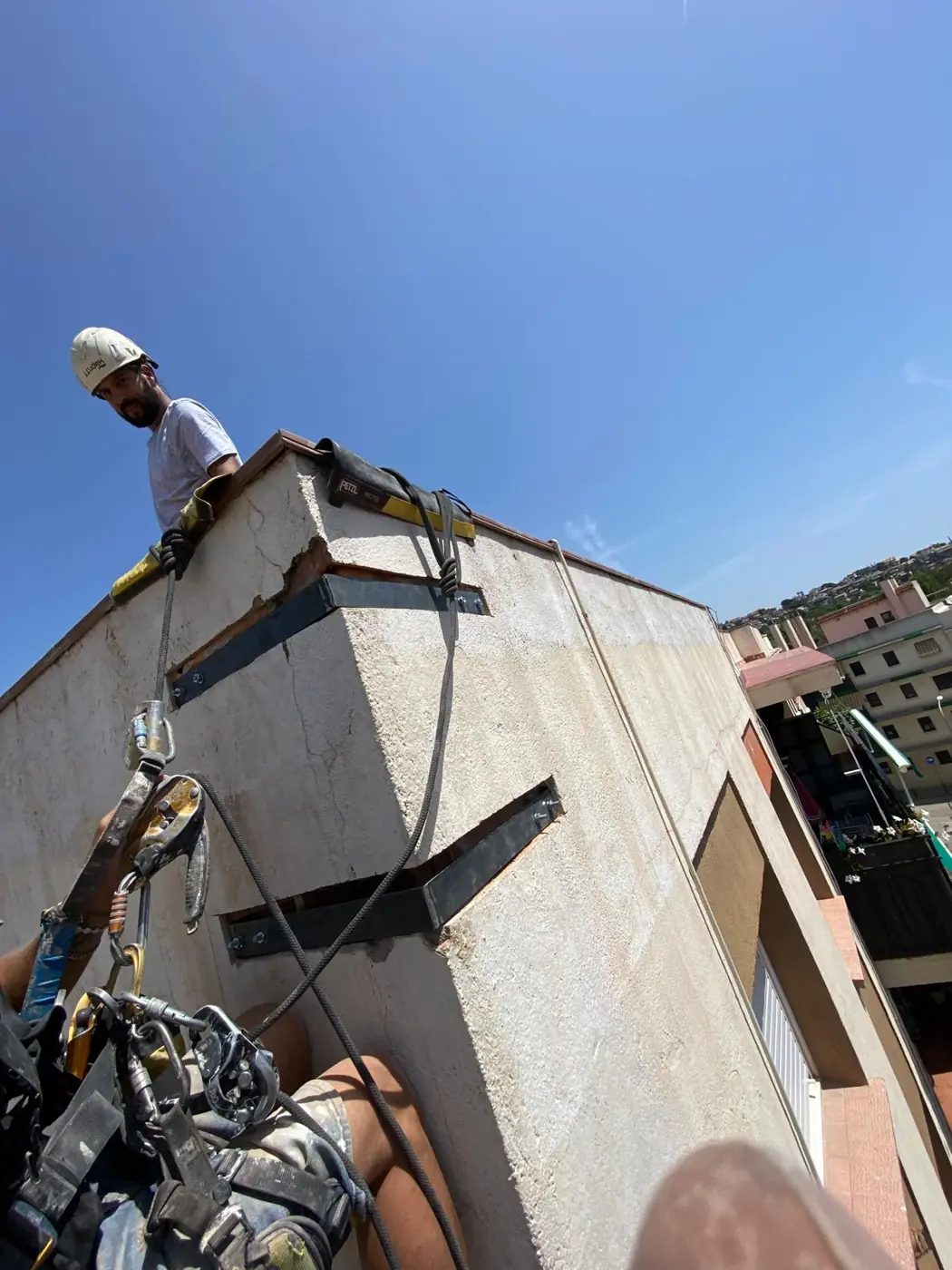 Técnicos colgados de cuerdas fijadas en la azotea, trabajando en una cornisa