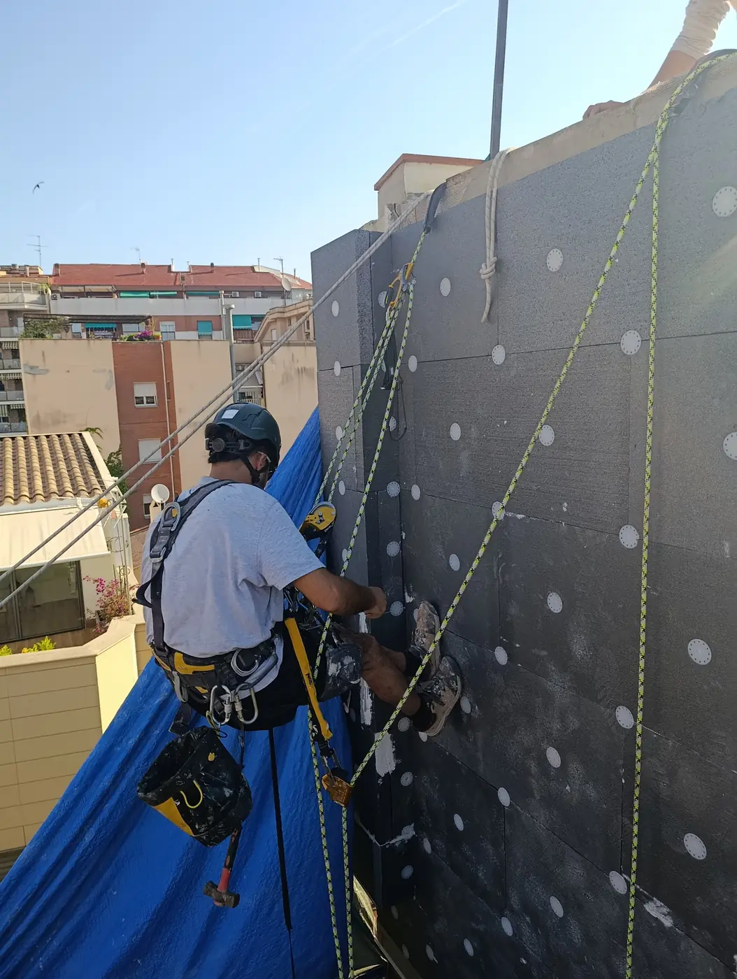 Técnico colgado instalando aislamiento SATE en una medianera de Barcelona